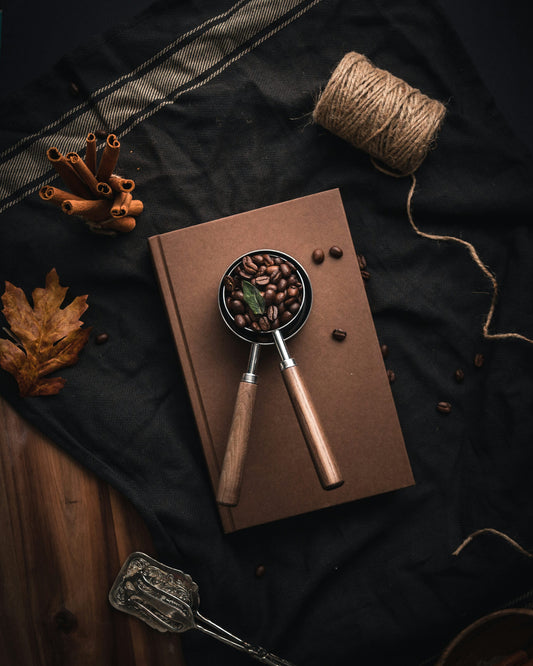 A wooden spoon filled with coffee beans on a neutral surface