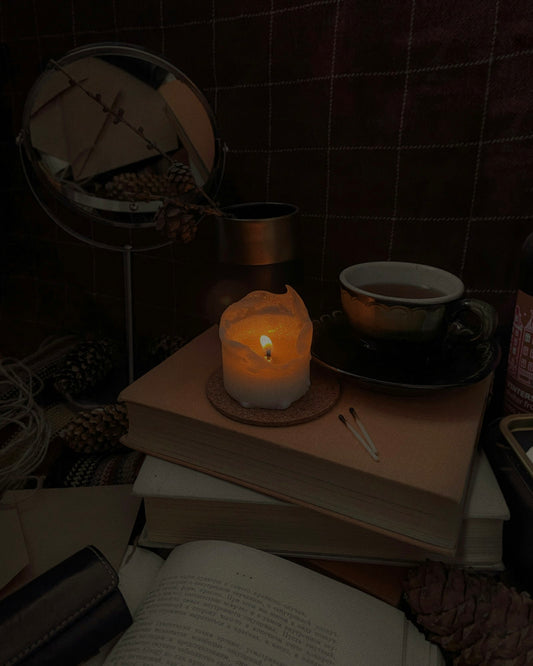 A lit candle on top of a book in warm, low light