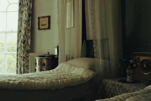 An unmade bed in a quiet room with soft light from a window