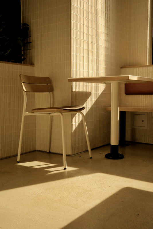 An empty chair and small table in warm sunlight, casting quiet shadows
